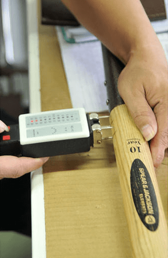 Moisture test being conducted on a wooden handle with a digital moisture meter